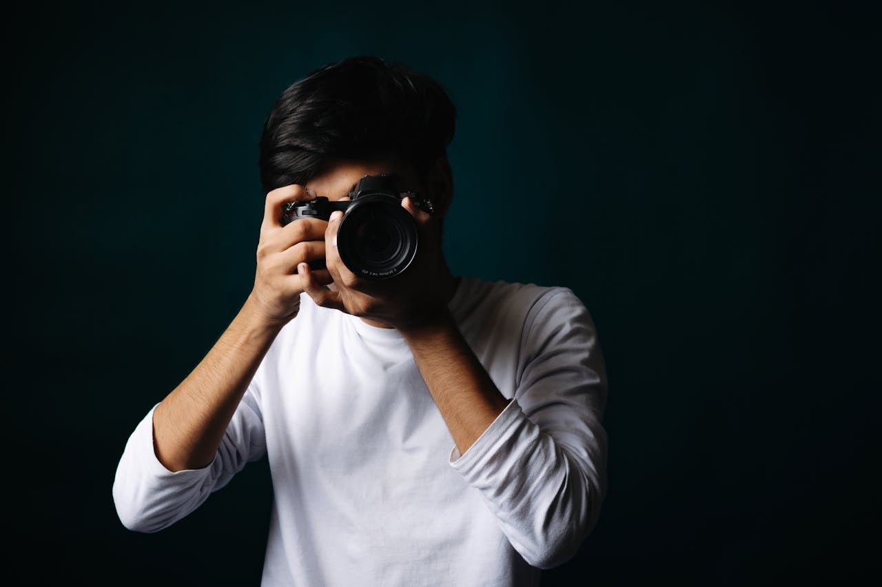 Portrait of a young photographer in a studio setting holding a camera.