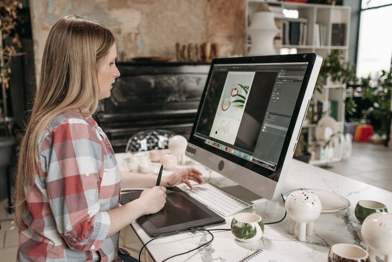Woman using a digital drawing tablet in a stylish office workspace, focused on graphic design.
